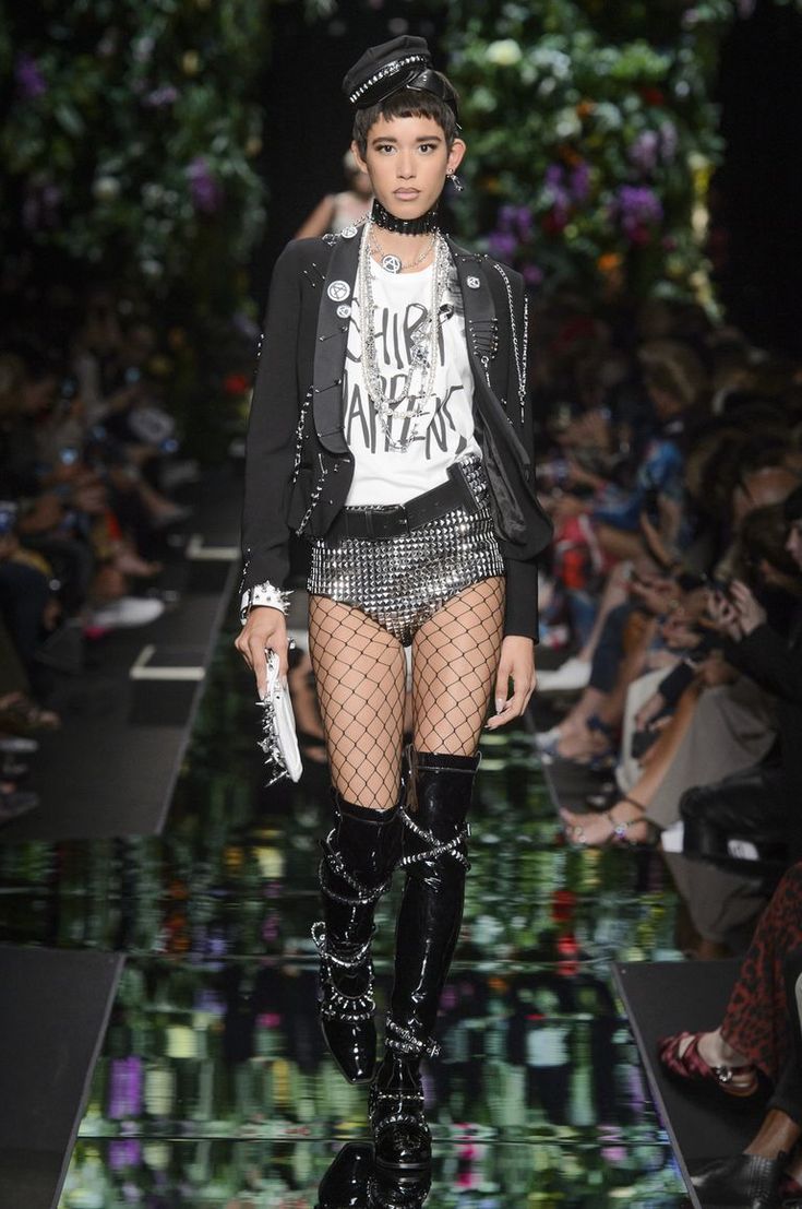 a model walks down the runway wearing fishnet stockings and thigh high boots