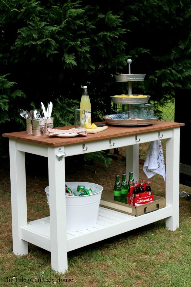 an outdoor table with drinks and snacks on it in the grass next to some trees