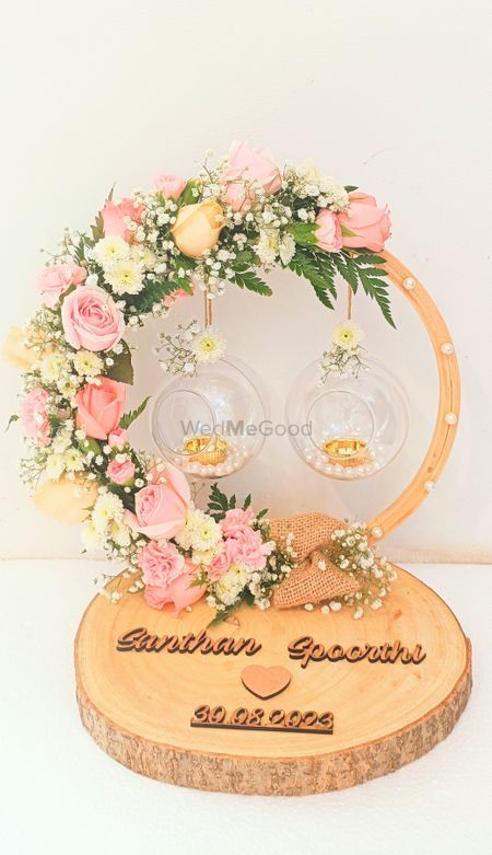 two wine glasses with flowers and greenery are on top of a wooden plaque