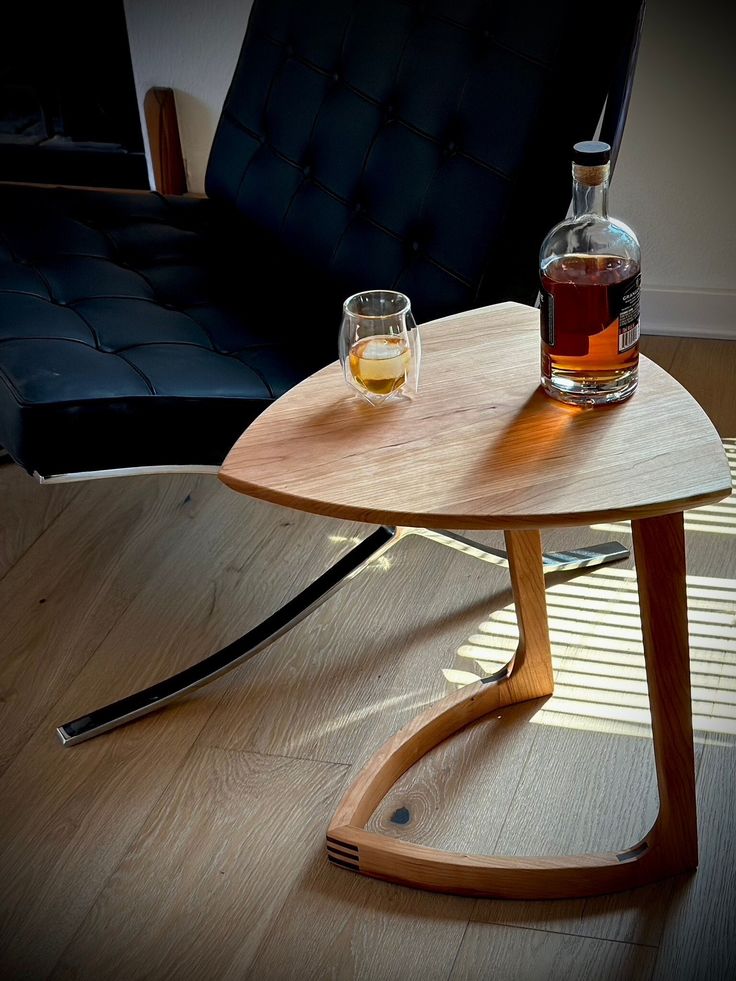 a wooden table with two glasses on it and a bottle of alcohol in the middle