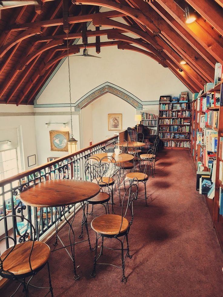 tables and chairs are lined up against the wall in an open area with bookshelves