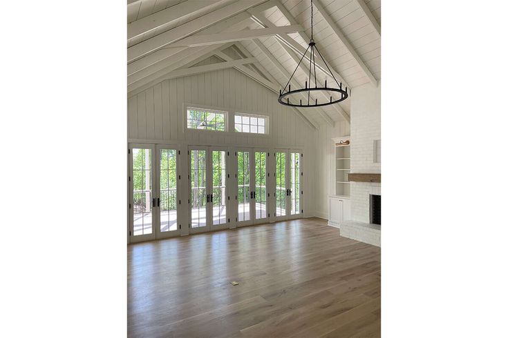 an empty living room with wood floors and white walls, large windows on both sides