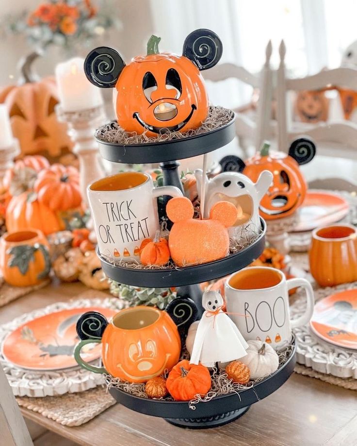 three tiered trays filled with halloween decorations and mickey mouse mugs on top of each other