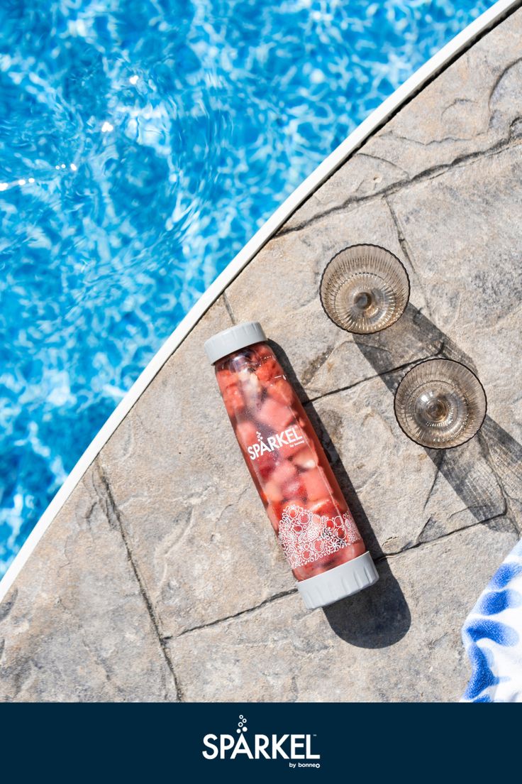 a bottle of sparkling water next to a pool