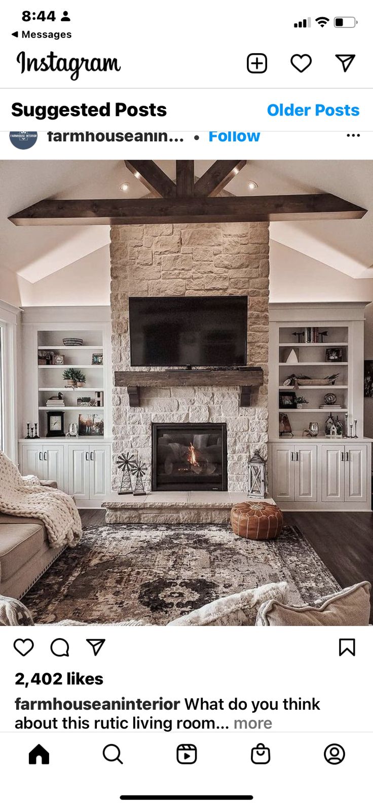 the living room is decorated in white and has a stone fireplace with built - in shelves