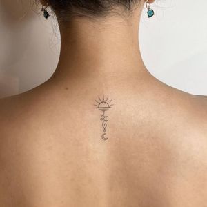 the back of a woman's neck with a sun and moon tattoo on it