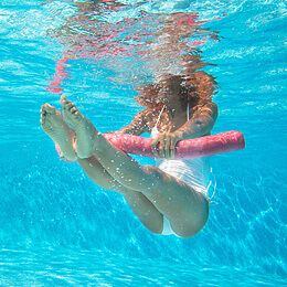 a woman in white swimsuit holding a pink surfboard under water