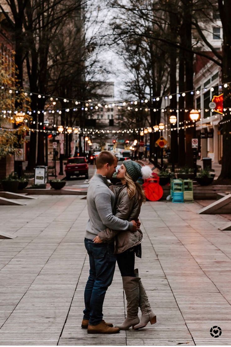 a man and woman standing next to each other on a sidewalk in front of trees