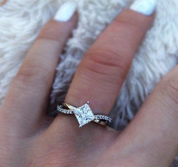 a woman's hand with a diamond ring on top of her finger and white nail polish