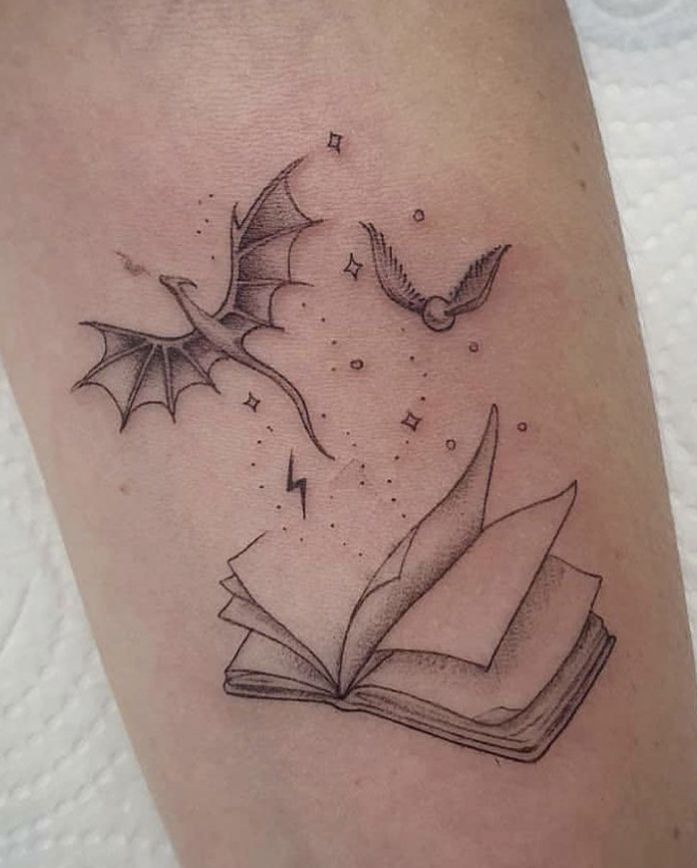 an open book with flying birds and stars on it's cover - up tattoo