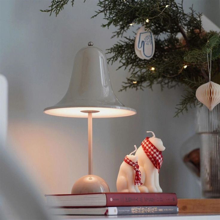 a table with a lamp, book and other items on it next to a christmas tree