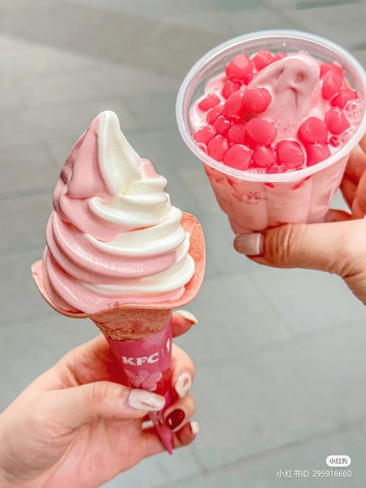 two people holding ice cream cones with pink and white toppings