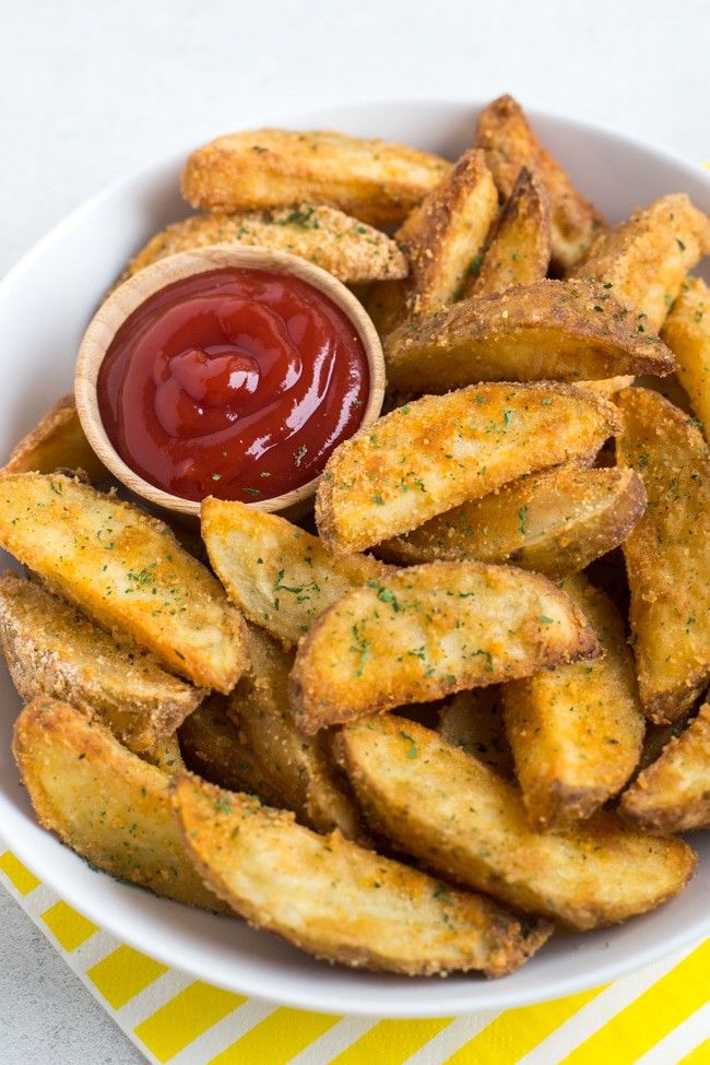 a bowl filled with french fries and ketchup on top of a yellow and white table cloth