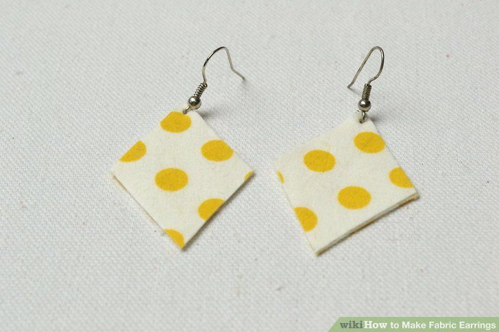 two square shaped earrings with yellow polka dots on white fabric, hanging from silver hooks