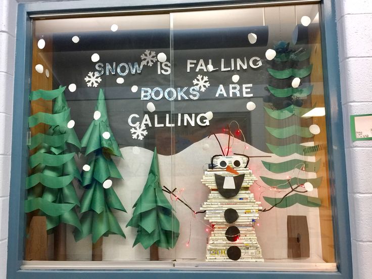 snow is falling books are calling window display with paper cut outs and trees in the background