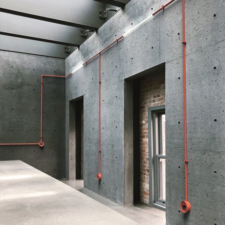 an empty room with concrete walls and red piping