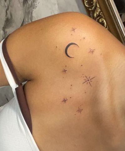 a woman's back with stars and a crescent tattoo on her left side ribcage