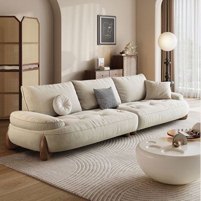 a living room filled with furniture and a large white rug on top of a hard wood floor