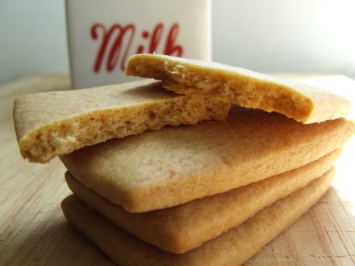 a stack of crackers sitting on top of a wooden table next to a cup