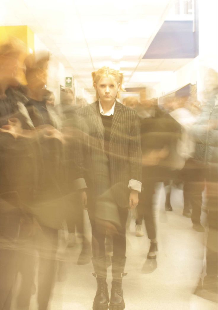 a blurry photo of a woman walking down a hallway with other people in the background