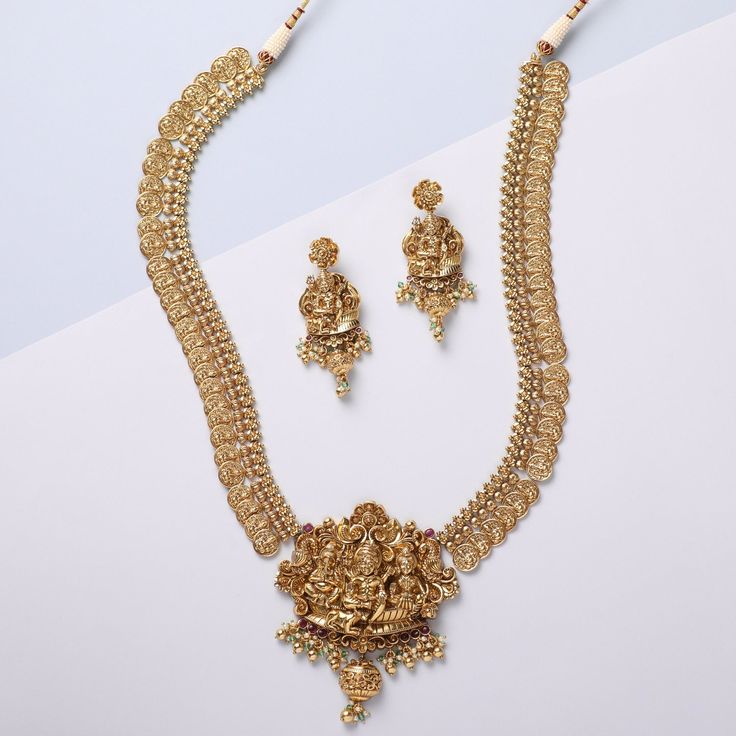 Description Infuse a classic twist to your festive look with the Mandira family's nakshi coin temple necklace. Embellished with nakshi motifs throughout, this 925 hallmark silver necklace portrays a detailed idol of Lord Shiva, Lord Ganesha, and Lord Kartikeya sitting together in a blessing posture. The necklace is completed with lustrous antique gold-tone plating. Elevate your festive appearance by pairing this necklace with other nakshi jewelry accessories. Product Information Materials used: Yellow Gold Jewelry For Puja Diwali, Yellow Gold Jewelry For Diwali Puja, 22k Gold Jewelry For Puja, Yellow Gold Tilla Jewelry For Navratri, Navratri Yellow Gold Tilla Jewelry, 22k Gold Temple Necklace With Tilla For Puja, Festive 22k Gold Temple Necklace With Pendant, 22k Gold Temple Jewelry For Puja, 22k Gold Cutdana Jewelry For Puja