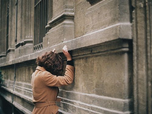 a woman leaning on the side of a building