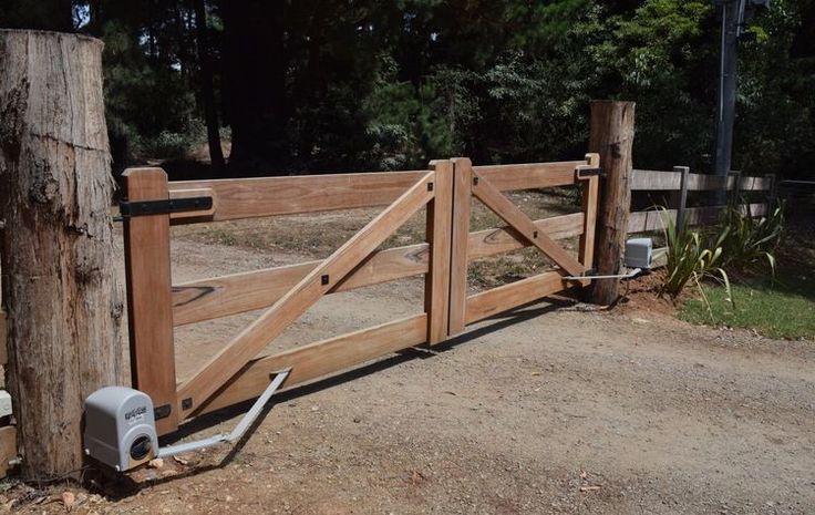 a wooden gate with an automatic water pump attached to it and some trees in the background