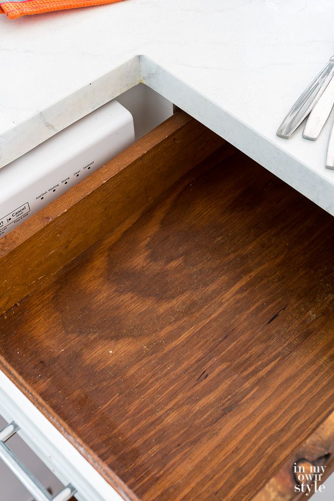 an open drawer with utensils in it on top of a white countertop