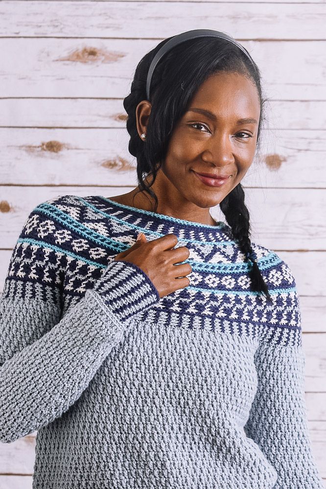 a woman wearing a sweater and smiling at the camera with her hands on her hips