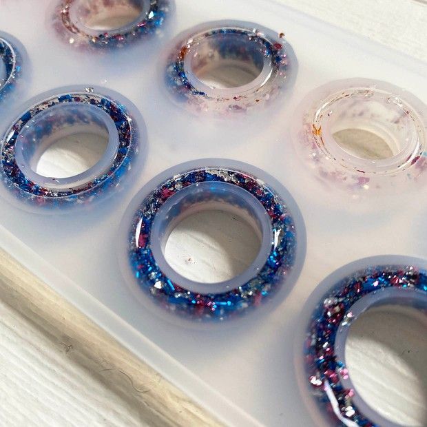 six blue and red glass rings sitting on top of a white tray next to each other