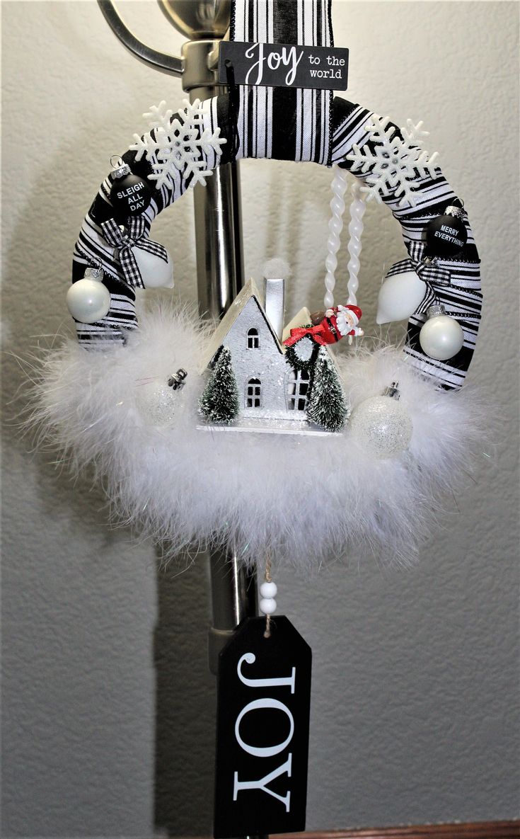 a christmas wreath hanging from the side of a door with white feathers and decorations on it