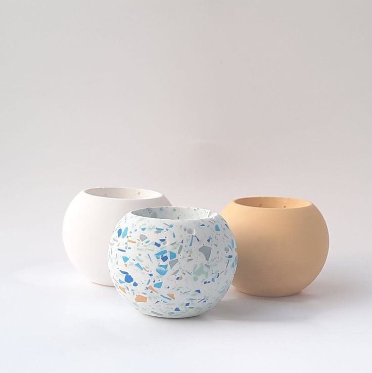 three vases sitting next to each other on a white surface