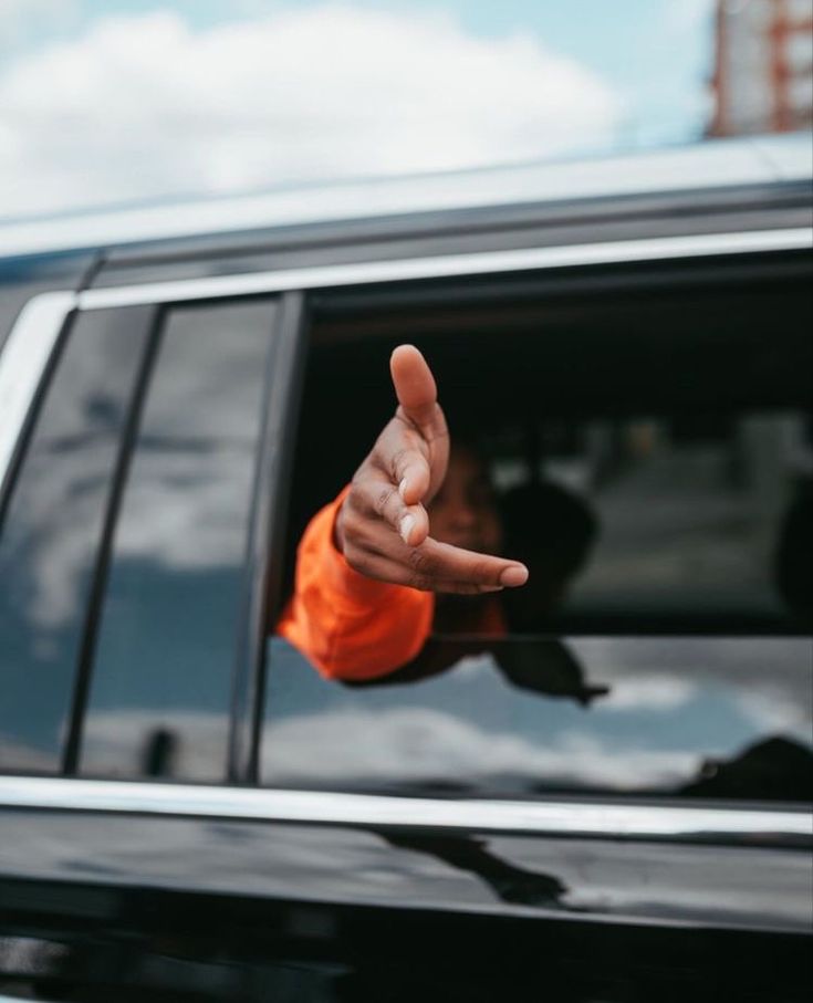 a hand pointing out the window of a car