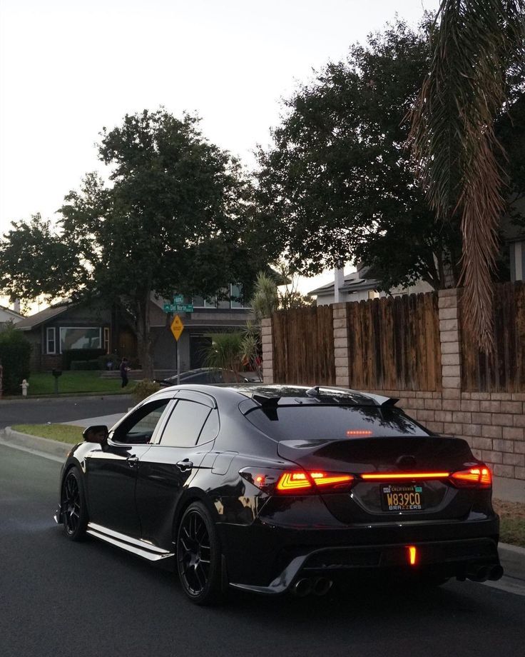 a black car is driving down the street