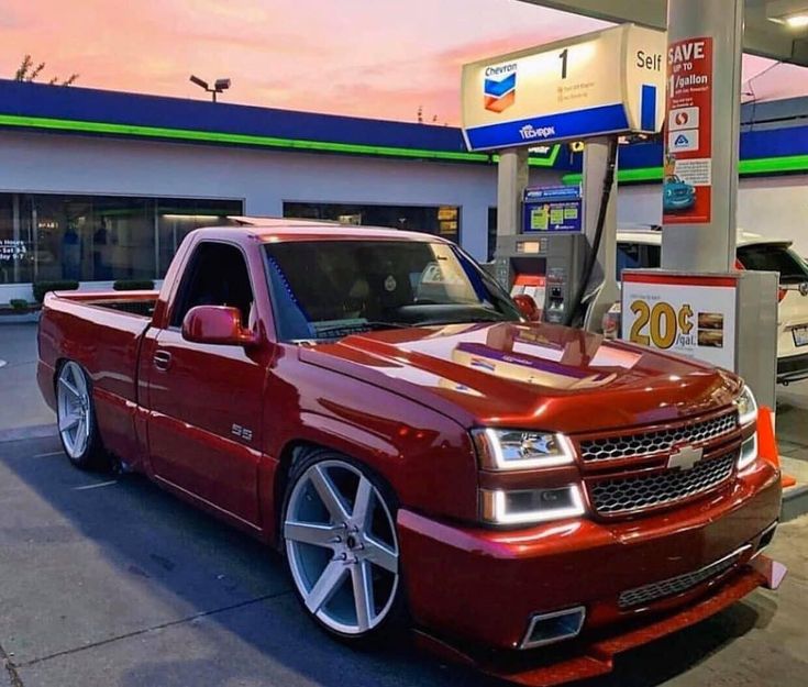 a red truck parked in front of a gas station