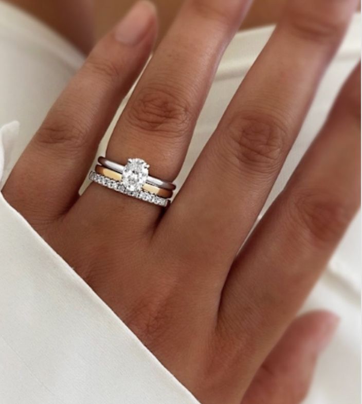 a woman's hand with a diamond ring on top of her finger and an engagement band