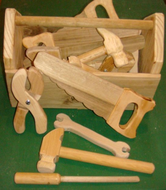 a wooden tool box filled with tools like hammers, nails and pliers on top of a green surface