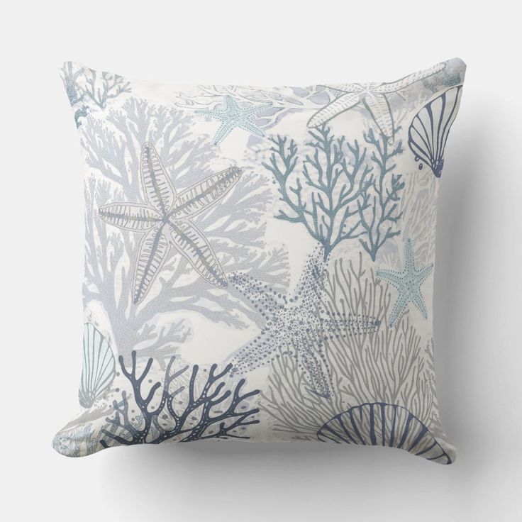 a blue and white pillow with starfishs on the front, and corals on the back