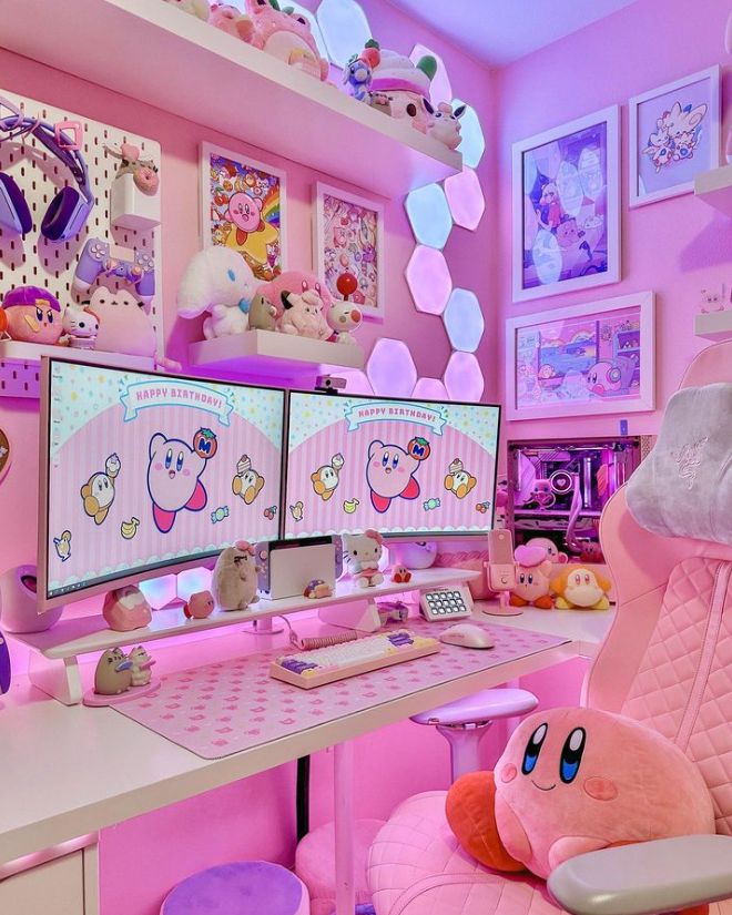 a pink room with two computer screens and stuffed animals