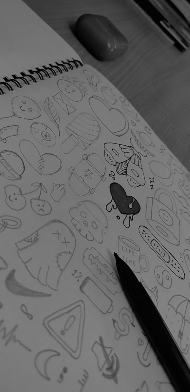 an open notebook with doodles on top of it and a computer keyboard in the background