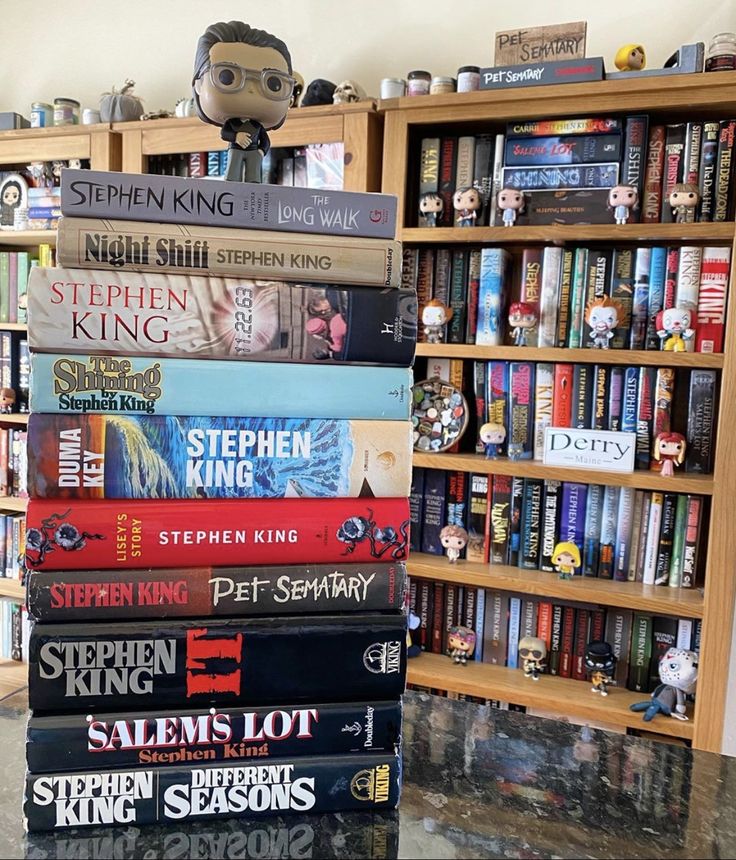 a stack of books sitting on top of a table next to a book shelf filled with books