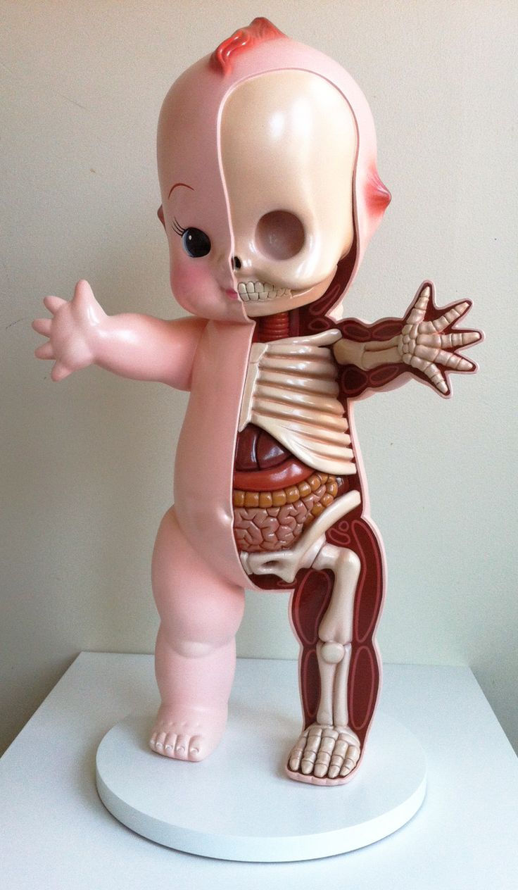 a small figurine of a human skeleton on a white pedestal with its arms outstretched