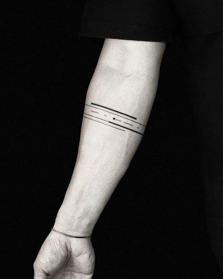 a black and white photo of a person's arm with a line tattoo on it