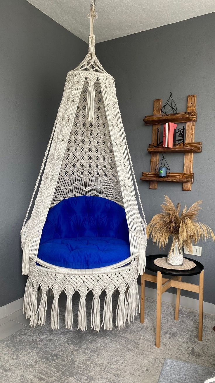 a white hammock hanging from the ceiling in a living room with blue cushions