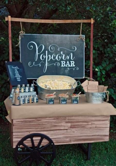 an outdoor movie party with popcorn bar and chalkboard sign on the table for guests to eat