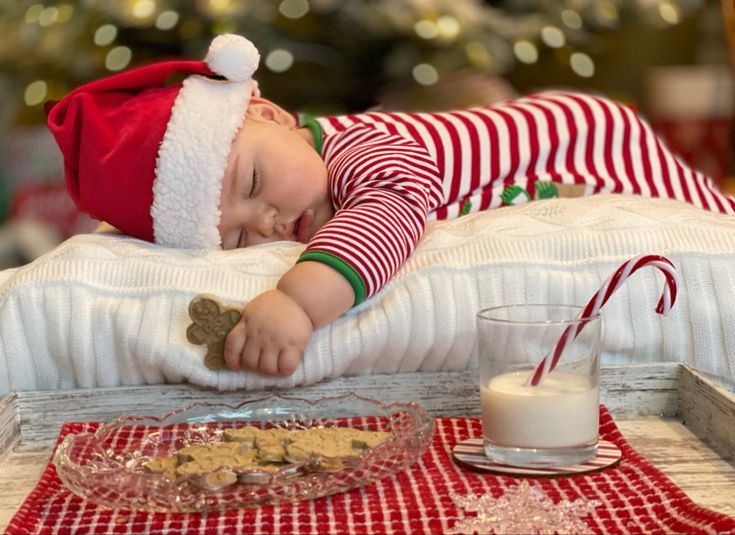 a small child laying on top of a bed next to a bowl of cookies and milk