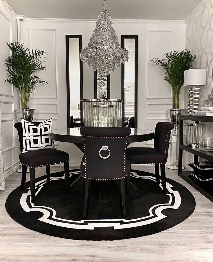 a black and white dining room with chairs, table and chandelier in the center