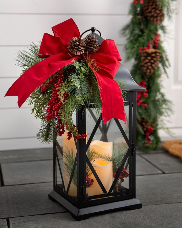 a lantern filled with candles sitting on top of a table next to christmas wreaths