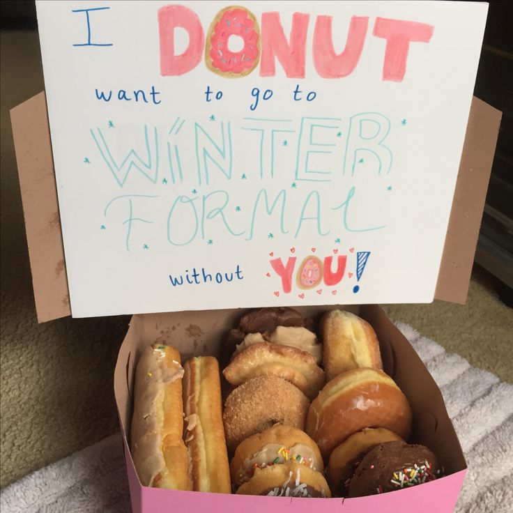 a pink box filled with donuts sitting on top of a white towel next to a sign