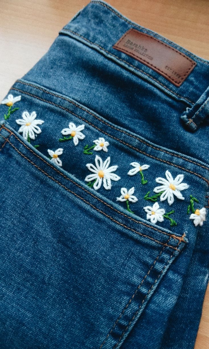 a pair of jeans with daisies embroidered on them